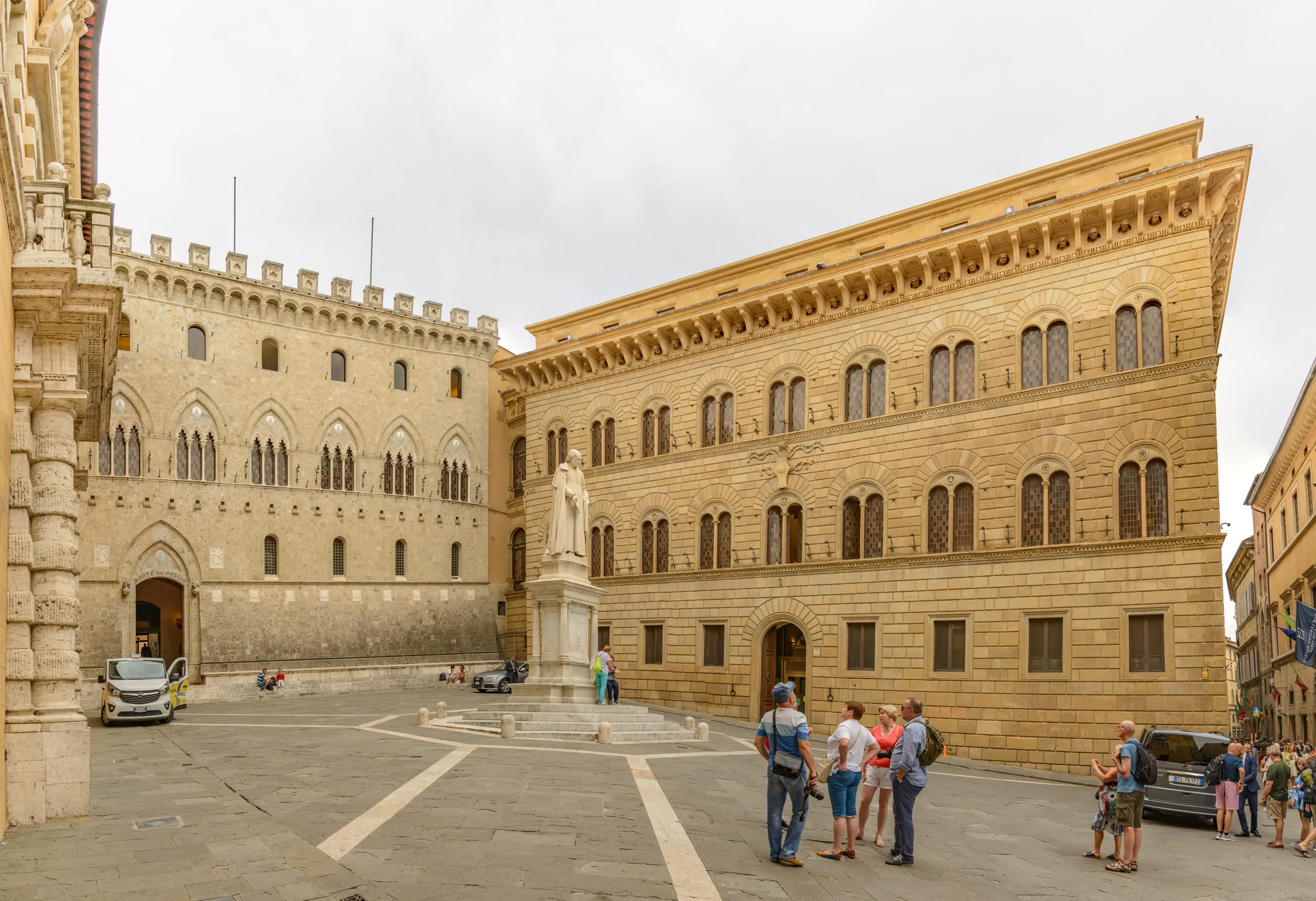 Piazza Salimbeni in Siena, with the crenellated facade of Rocca Salimbeni on the left, the statue of Sallustio Bandini at the centre and the Palazzo Spannocchi on the right